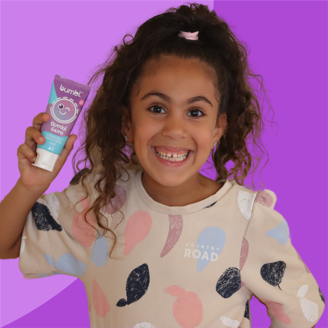 Happy child holding bumbl co bubblgum toothpaste with cheeky smile